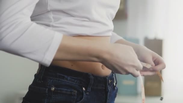 Vue latérale de la jeune femme mesurant sa taille avec du ruban à mesurer — Video
