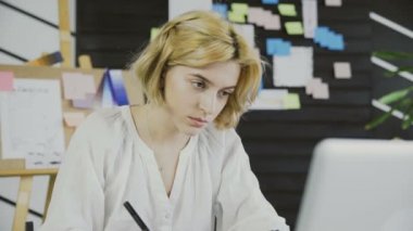 Ofiste grafik tabletle çalışan genç bir kadın.