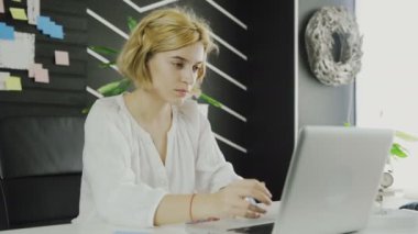 Modern ofisinde dizüstü bilgisayarla çalışan kendine güvenen iş kadınından uzaklaşın.