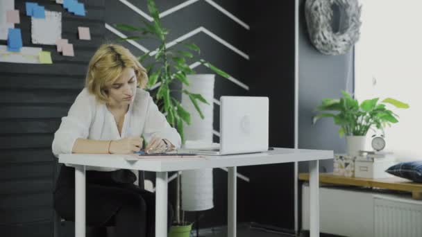 Affärskvinna skriver ner något på klistermärken när du sitter vid bordet — Stockvideo