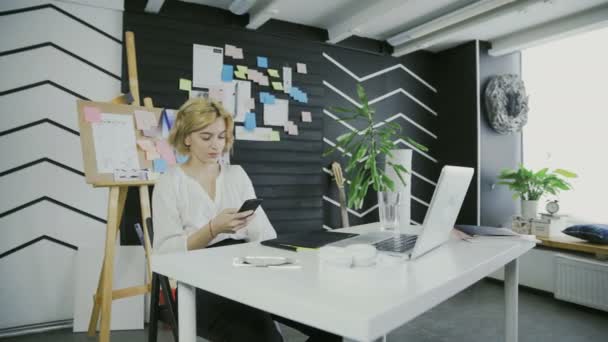 Jeune femme utilisant l'application sur smartphone au bureau — Video