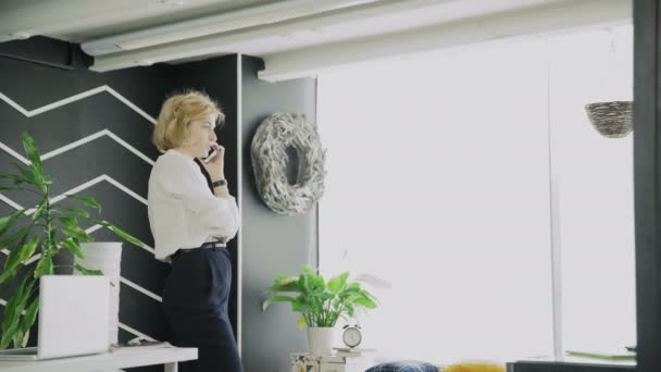 Блондинка разговаривает по телефону. Рабочая женщина выступает на мобильном телефоне в офисе — стоковое видео