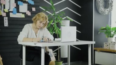 İş kadını masada otururken çıkartmalara bir şeyler yazıyor.