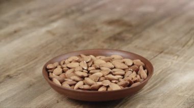 Kadın, yemek için kasesinden bir avuç badem topluyor. Sol tarafıma fındık kaçtı.