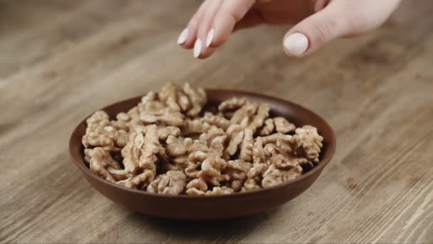 Žena zvedne hrst vlašských ořechů, aby se najedla, ze své misky. vzal matici na pravé straně — Stock video