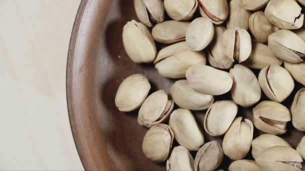 Pistachio nuts in wooden bowl top view. — Stock Video