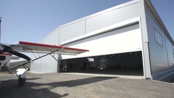 Aviones pequeños fuera del hangar. La puerta se abre. Parte visible de una aeronave pequeña — Vídeo de stock