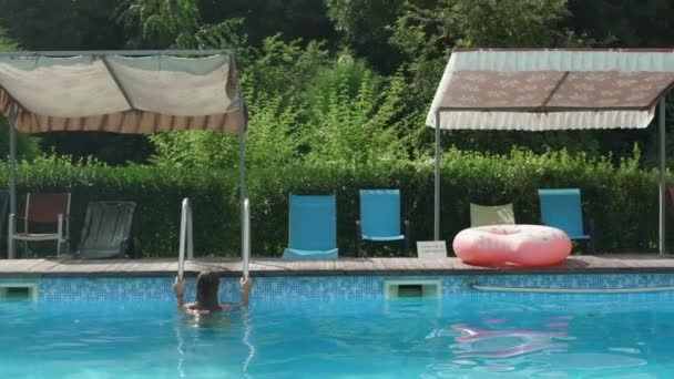 Jonge aantrekkelijke blanke vrouw in bikini verlaat het zwembad door metalen ladder slow motion shot — Stockvideo