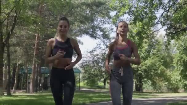 Dos mujeres corredoras corriendo en el Sunny City Park haciendo ejercicio al aire libre . — Vídeos de Stock