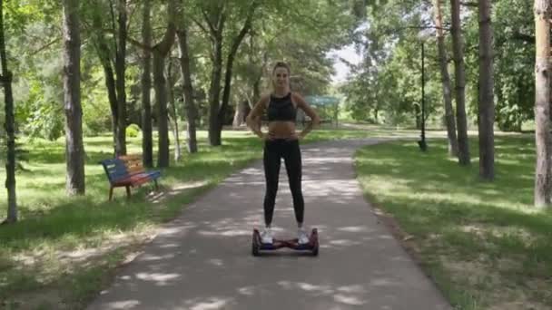 Belle fille avec corps athlétique sur hoverboard marche dans le parc — Video