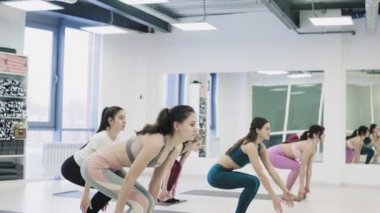 Yoga öğrencileri Virabhadrasana 'nın ışık stüdyosunda Savaşçı pozu üzerinde çalışıyorlar..