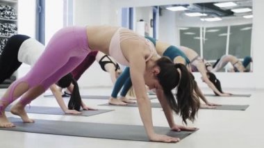 Spor ve sağlıklı yaşam tarzı. Kadın eğitmen, beyaz fitness merkezinde müşterilerle baş aşağı poz veriyor.