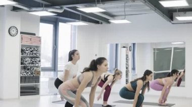 Yoga öğrencileri minderlerin üzerinde durup yoga pozu veriyorlar..