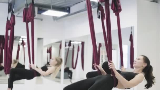 Mooie vrouwen zweven in hangmat in de lucht ruimte van de studio binnen. — Stockvideo