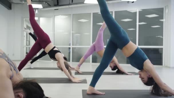 Estudiantes de yoga practican Warrior pose Virabhadrasana en estudio de luz cómoda . — Vídeos de Stock