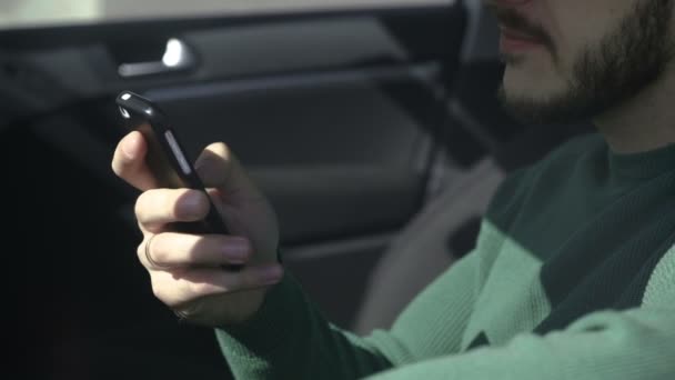 Brutal skäggiga man med hjälp av en telefon som sitter i bilen. — Stockvideo