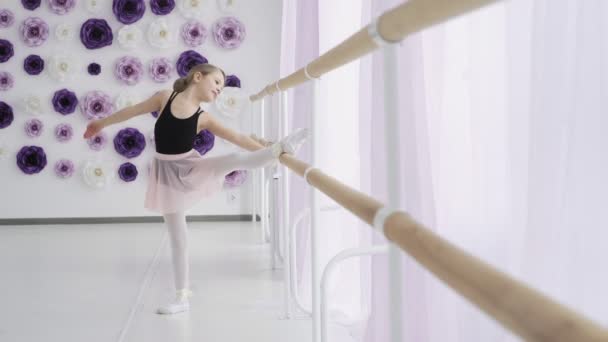 Retrato de la joven bailarina estirándose cerca de la barra de ballet en el estudio . — Vídeo de stock