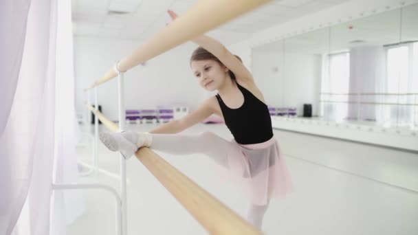 Μικρά κορίτσια που χρησιμοποιούν μπάρα μπαλέτου όταν κάνουν ασκήσεις τεντώματος ποδιών στο στούντιο χορού — Αρχείο Βίντεο
