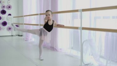 Dans stüdyosunda egzersiz yaparken bale çubuğu kullanan küçük bir kız.