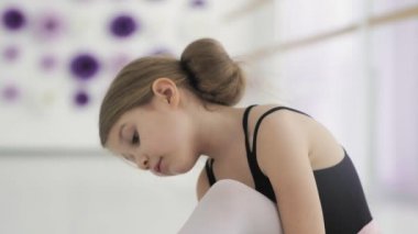 Eğitimden önce bale ayakkabılarını bağlayan sevimli balerin.