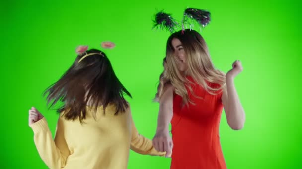 Красивые девушки в смешных шляпах танцуют на зеленом экране  . — стоковое видео