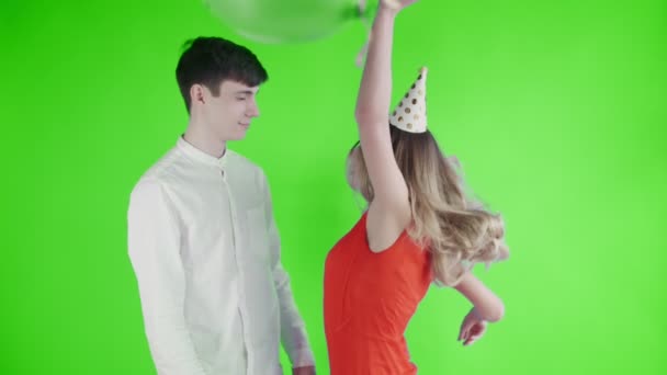 Young woman and man are dancing under colorful confetti on a green screen . — Stock Video