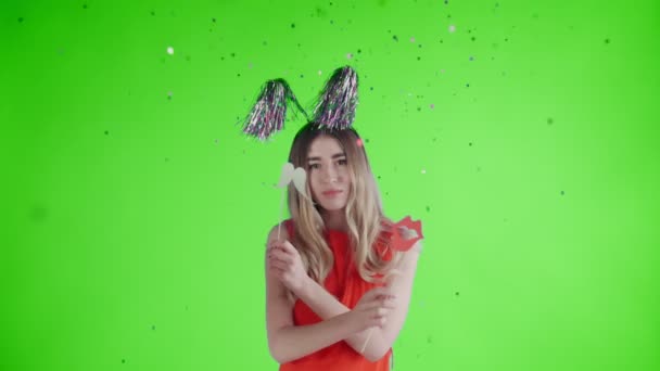 Hermosa chica en sombrero de fiesta están bailando bajo la caída de confeti y globos en una pantalla verde  . — Vídeos de Stock