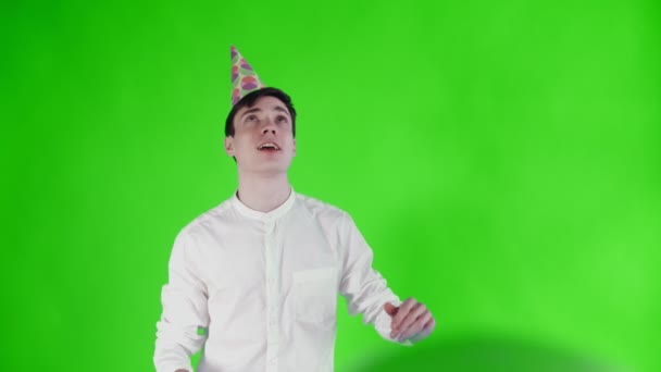 Young man in party hat is dancing under Balloons on a green screen . — Stock Video