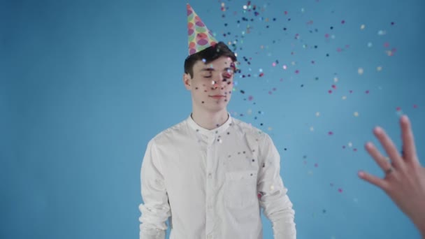 Confetti was thrown at the young man on a blue background. — Stock Video