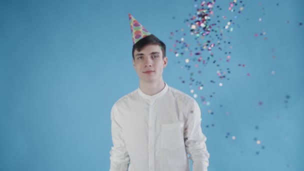 Confetti was thrown at the young man on a blue background. Slow motion — Stock Video