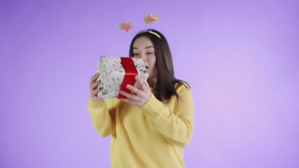 Receiving a gift girl with funny hat rejoices on a purple background — Stock Video