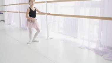 Genç balerin stüdyoda bale barının yanında egzersiz yapıyor..