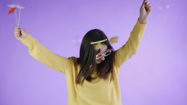 Belle jeune femme avec chapeau drôle et lunettes est la danse seule sur un fond violet . — Video