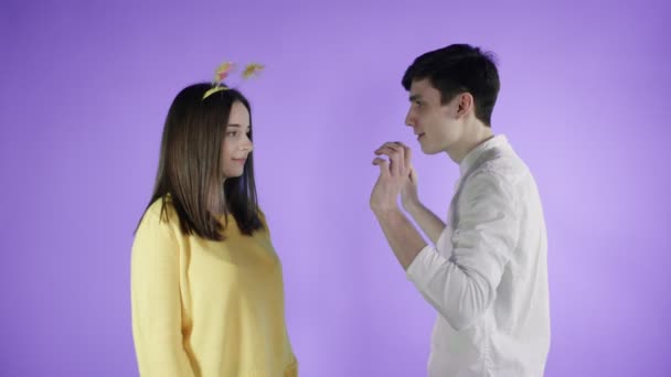 Νεαρή γυναίκα και άντρας χορεύουν σε πολύχρωμα κομφετί σε μωβ φόντο. — Αρχείο Βίντεο