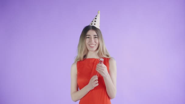 Mujer joven explotando galleta confeti sobre un fondo púrpura . — Vídeos de Stock