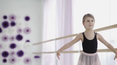 Genç, inanılmaz güzel balerin beyaz stüdyoda dans ediyor.