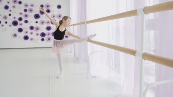 Kleine Mädchen mit Ballettbarre bei Beinstreckübungen im Tanzstudio — Stockvideo