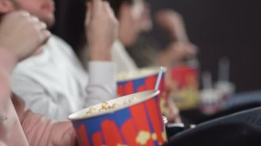 Sinemadaki arkadaşlar film izliyor kola içiyor ve patlamış mısır yiyorlar..