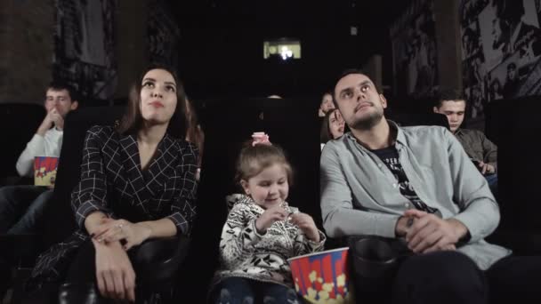 Jovem e mulher com uma criança estão assistindo a um filme . — Vídeo de Stock