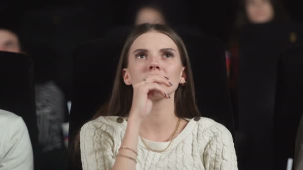 Közelkép egy ijedt fiatal nő használja a kezét, hogy eltakarja az arcát, miközben néz egy horror film. — Stock videók