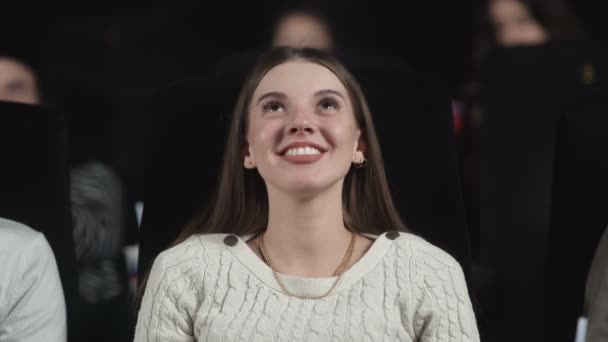 Une jeune femme au cinéma commence à sourire et à rire — Video