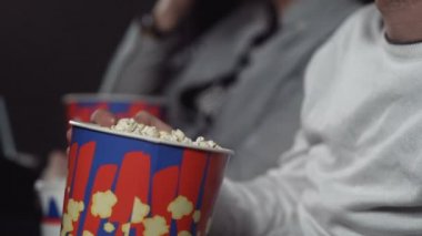 Sinemada patlamış mısır yiyip film izleyen bir adam..