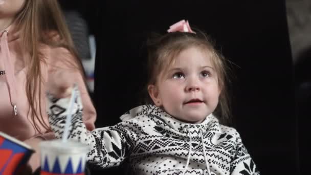 Lähikuva pikkutyttö katselee elokuvaa ja syö popcornia — kuvapankkivideo