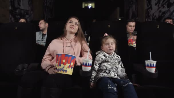 Menina e mãe estão assistindo a um filme e comendo pipocas — Vídeo de Stock