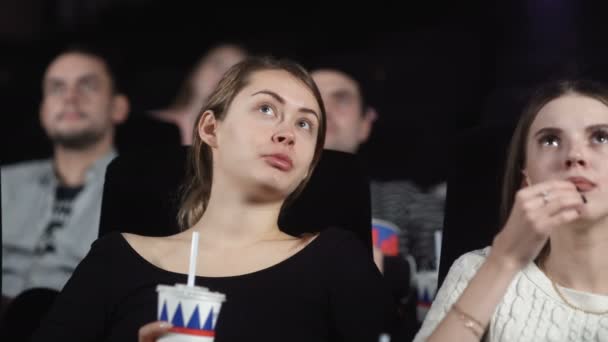 Dolly mossa di tre belle amiche stanno mangiando popcorn e guardando un film al cinema — Video Stock