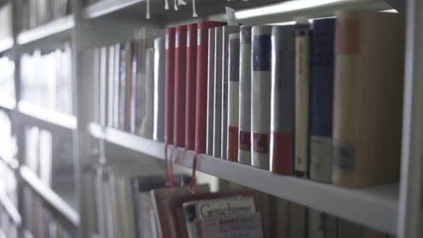 Dolly movimiento de estantes de la biblioteca con un montón de libros . — Vídeos de Stock
