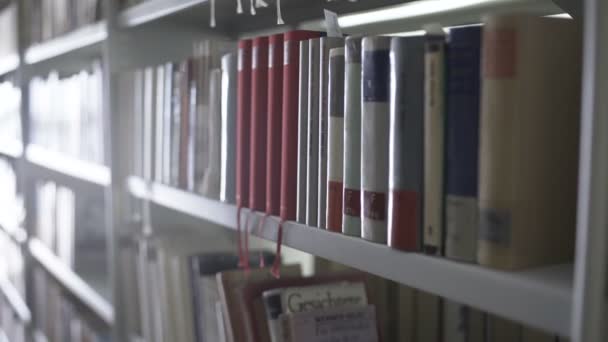 Dolly mover de prateleiras da biblioteca com lotes de livros . — Vídeo de Stock