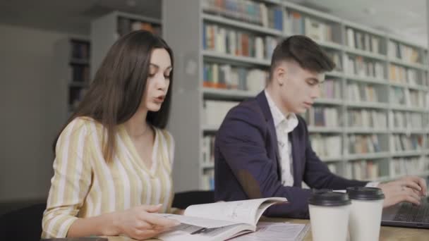 Zwei kaukasische Universitätsstudenten bereiten sich auf ihre Prüfung in der Bibliothek vor — Stockvideo