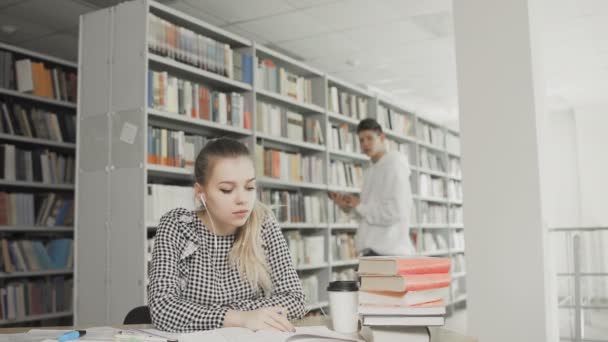 Dos estudiantes universitarios caucásicos preparándose para el examen en la biblioteca — Vídeos de Stock