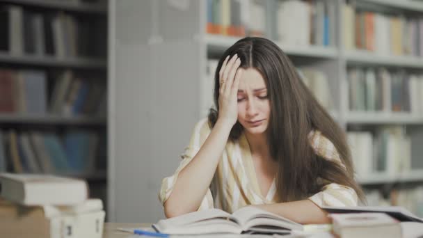 Estudiante cansado se prepara para el examen en la biblioteca universitaria — Vídeos de Stock